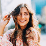 Brunette woman with sensitive teeth smiles because she safely whitened her teeth at Optima Dental Spa