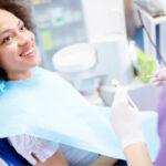 Curly-haired woman smiles before receiving root canal therapy at Optima Dental Spa