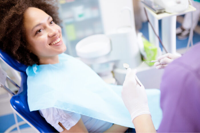 Curly-haired woman smiles before receiving root canal therapy at Optima Dental Spa