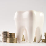 A tooth next to piles of coins to depict how to pay for dental care at Optima Dental Spa