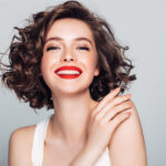 Brunette woman with red lipstick smiles after receiving safe BOTOX at the dentist