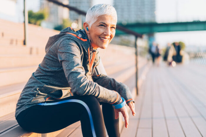Woman with a dental bridge smiles while taking a break from her run in the city