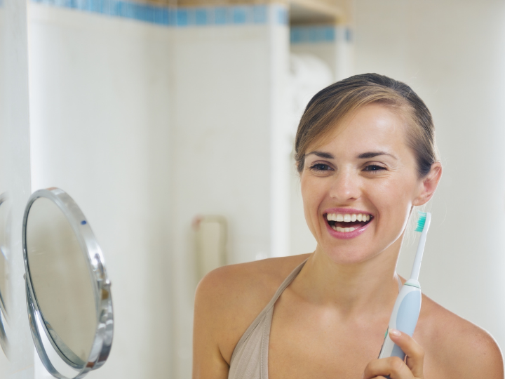 Woman With Electric Toothbrush - Optima Dental Spa